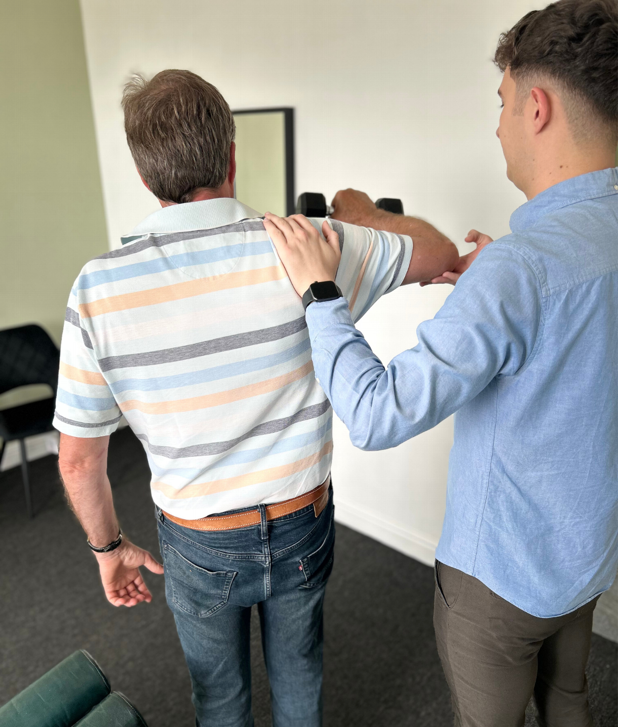 Chiropractor assisted patient with rehabilitation exercise to help with patient pain and loss of strength, taking place in a clinical modern chiropractic clinic setting